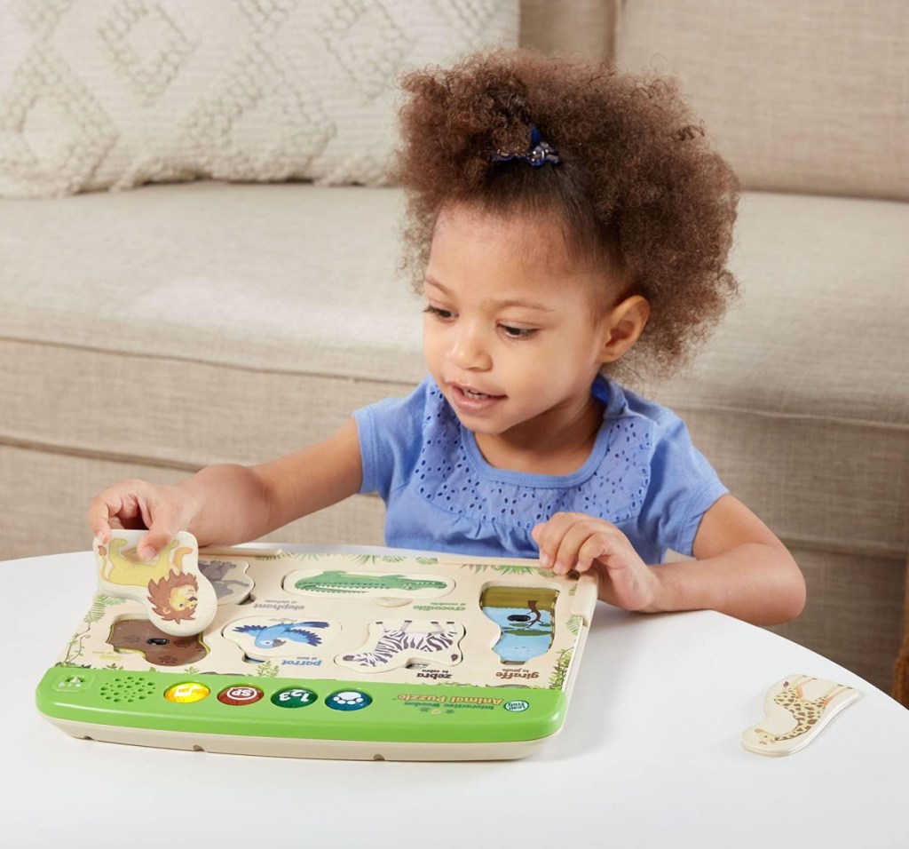 Girl playing with an interactive LeapFrog wooden puzzle