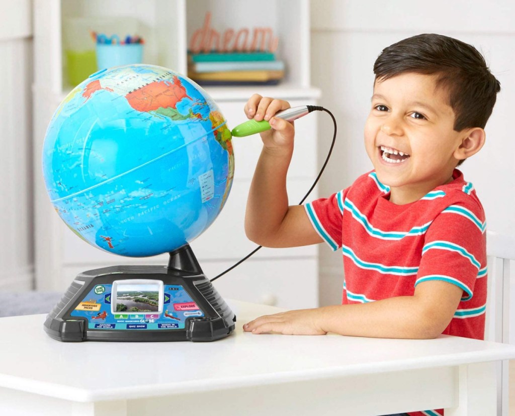 A boy at a table playing with the LeapFrog My Adventures Globe