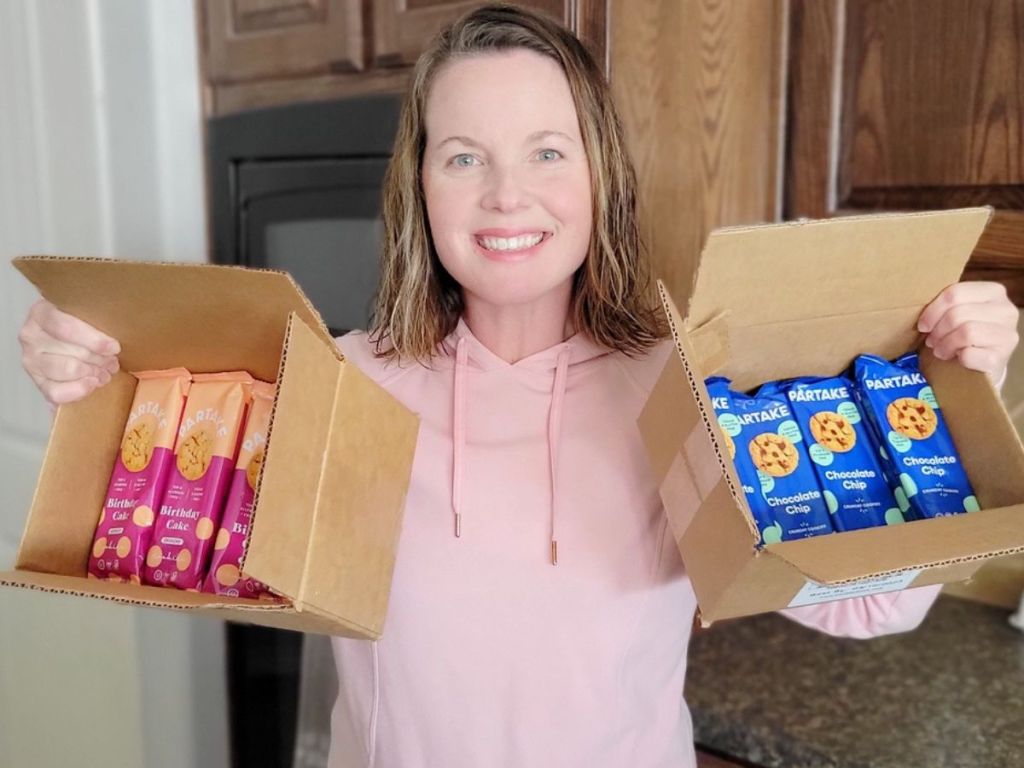 woman holding two cases of cookies