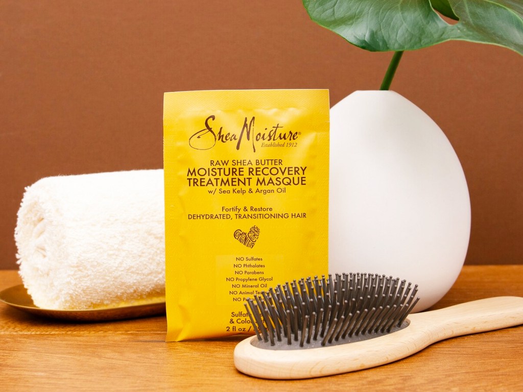 SheaMoisture Recovery Treatment Masque next to hair brush and rolled up towel