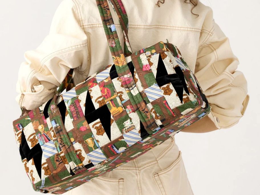 Woman carrying a Vera Bradley Harry Potter Hogwarts Library Patchwork Small Original Duffel over her shoulder