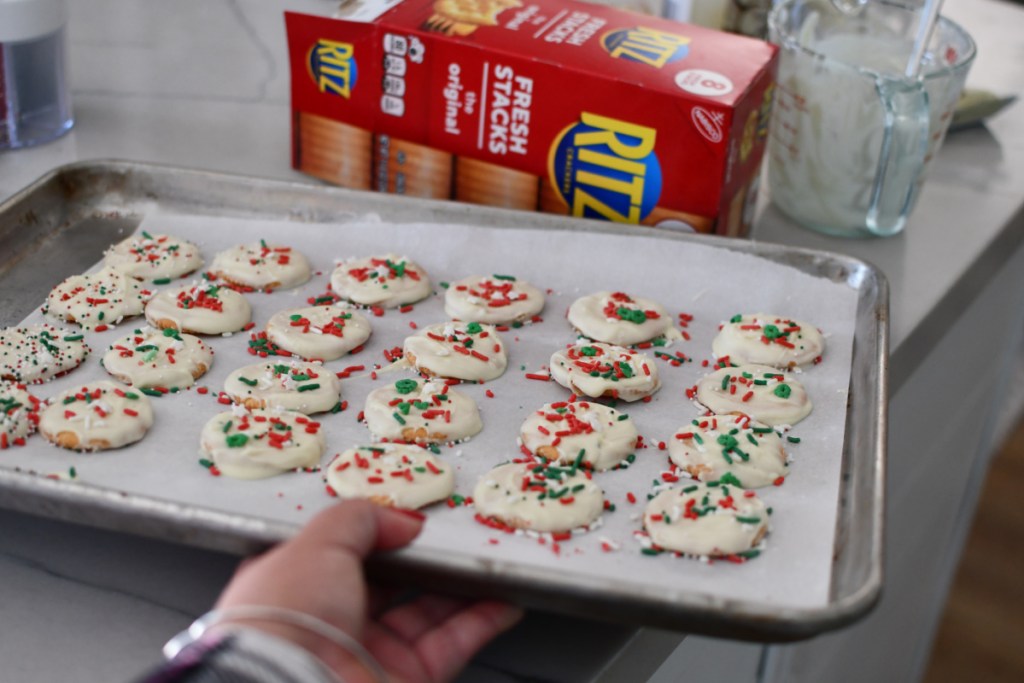 hand holding a baking shit with white chocolate christmas cookies that are like thin mints