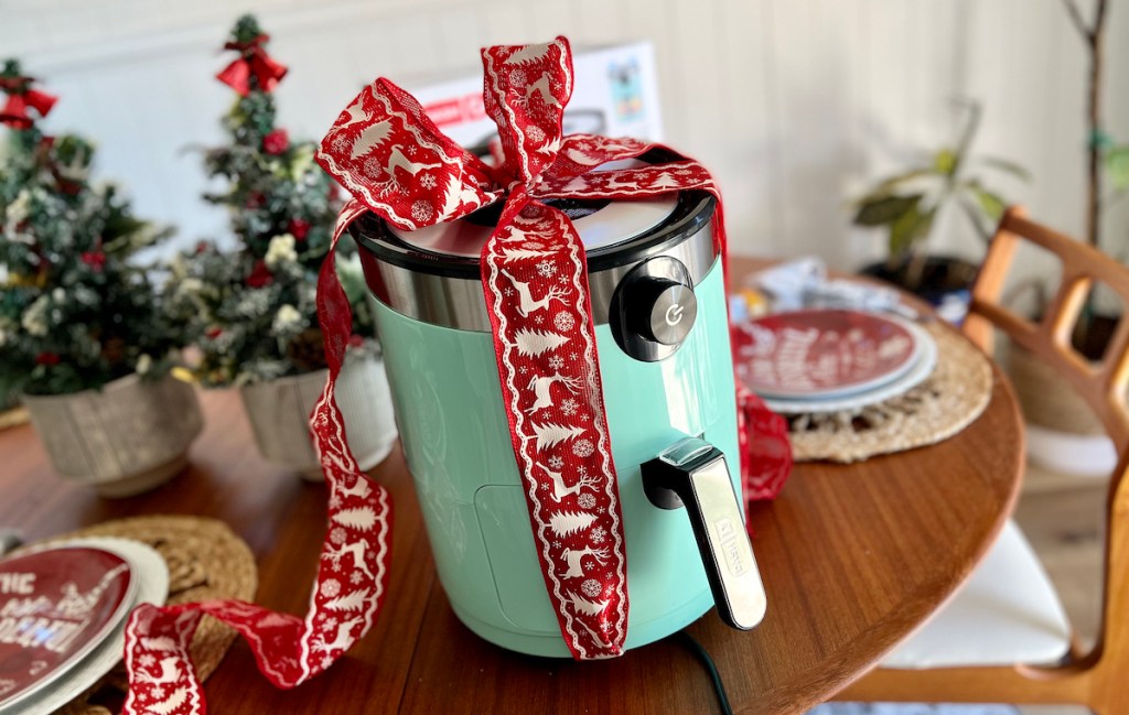 blue dash air fryer on wood table with red holiday bow