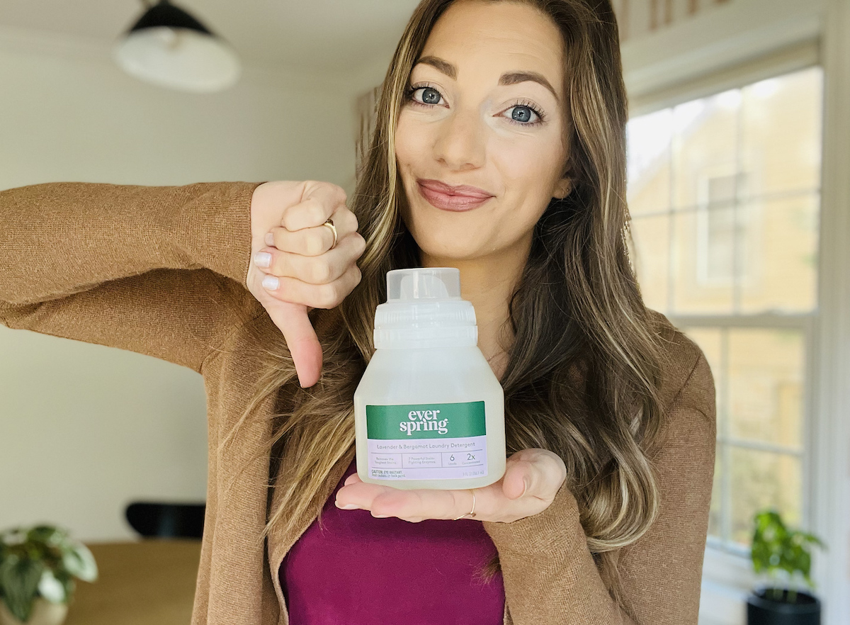 woman giving thumbs down holding travel size bottle of white is the best laundry detergent
