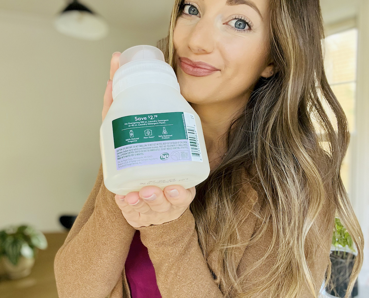 woman holding travel size bottle of everspring laundry detergent