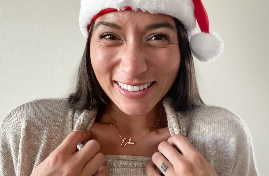 woman wearing santa hat showing off gold name necklace