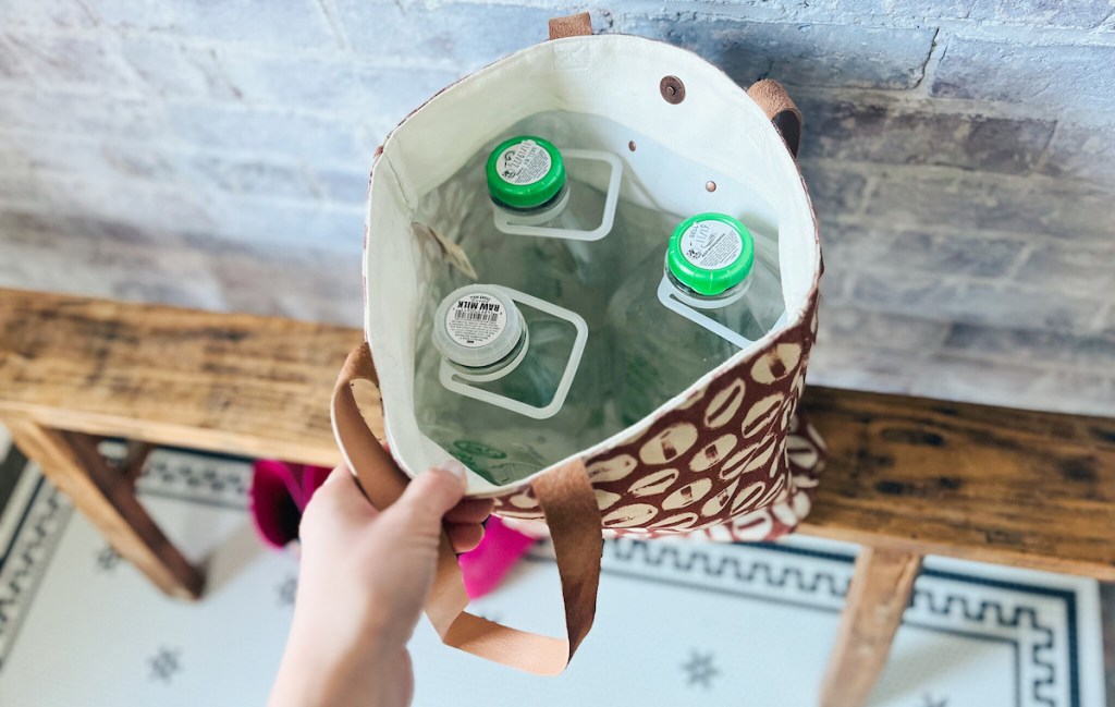 hand holding open bag full of raw milk glass jugs