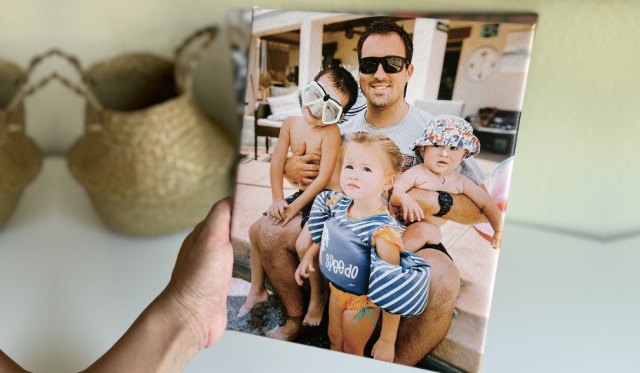 hand holding canvas print with man and three boys