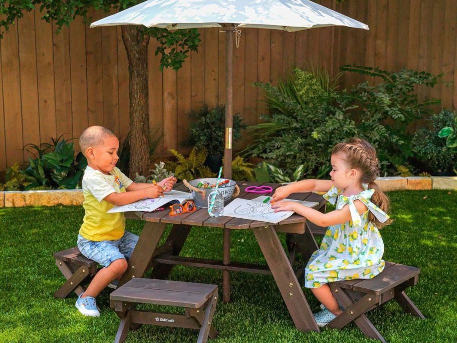 children sitting at KidKraft Octagon Kid's Picnic Table, Stools & Umbrella 6-piece Set