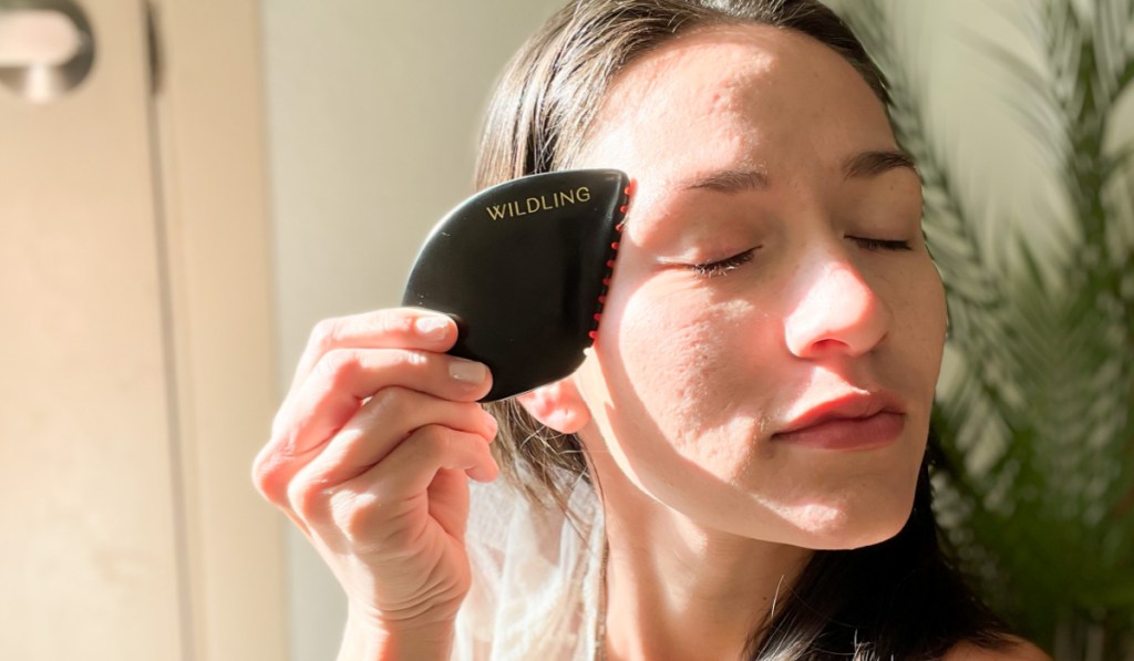 woman using gua sha on face