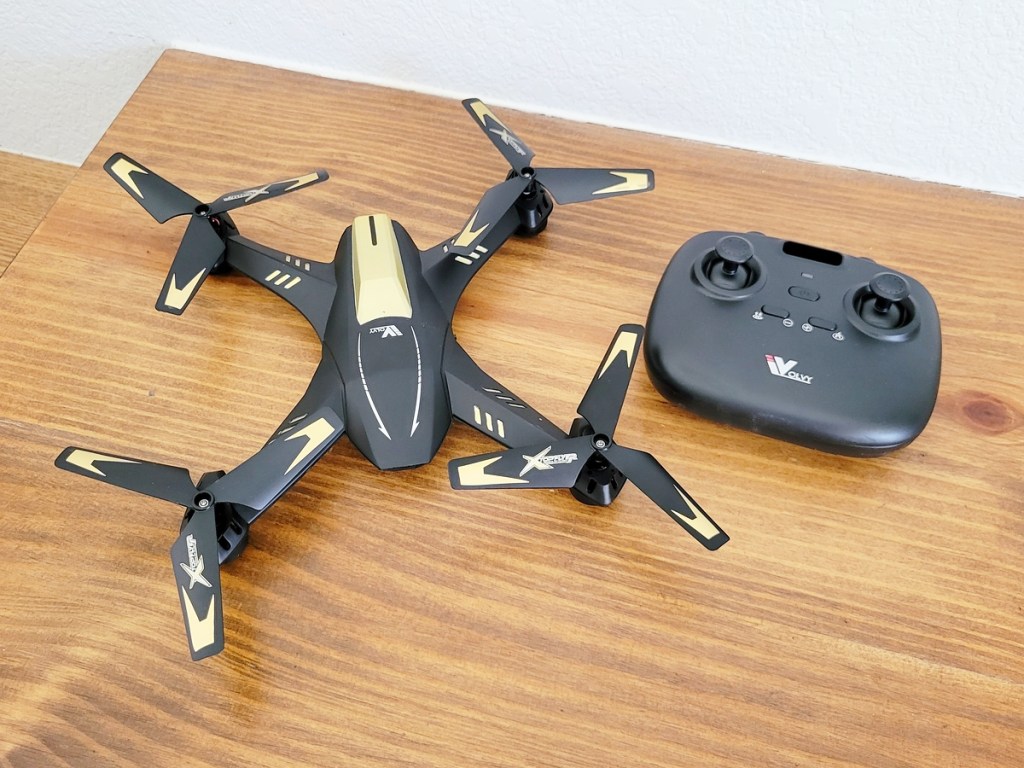 black and yellow drone and it's remote on a wood table