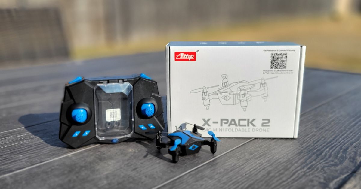 Attop Mini Drone, controller and box it comes in sitting on a wooden picnic table