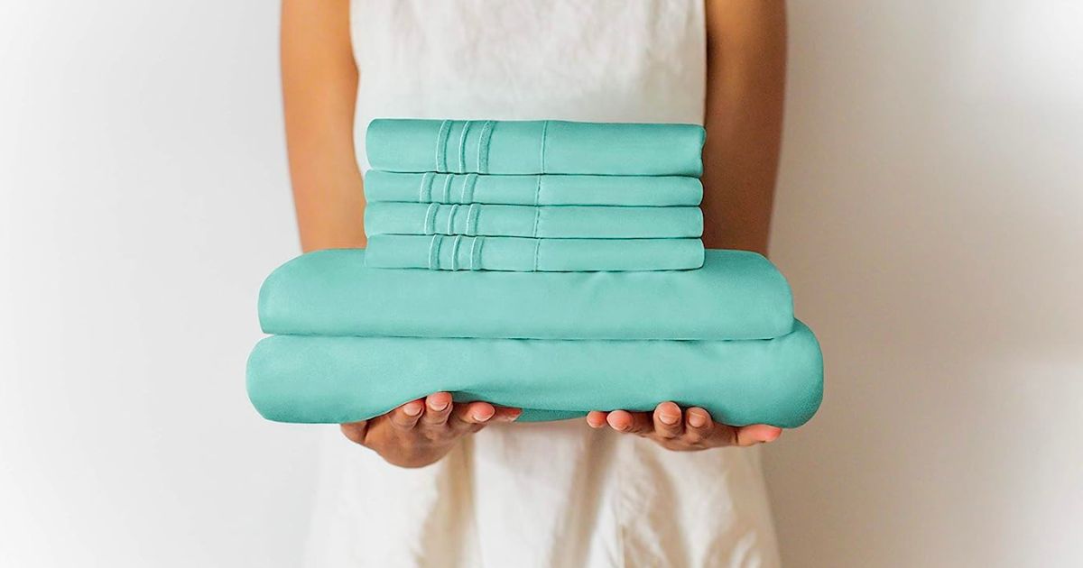 a woman holding a stack of CGK unlimited sheets in spa blue