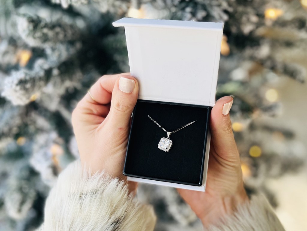 holding necklace in jewelry box near christmas tree