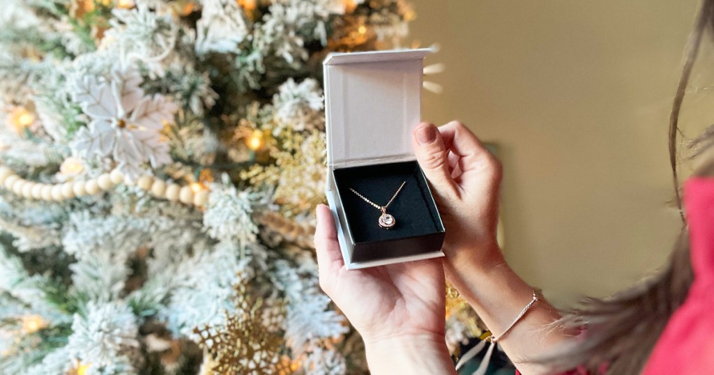 holding necklace in jewelry box near christmas tree