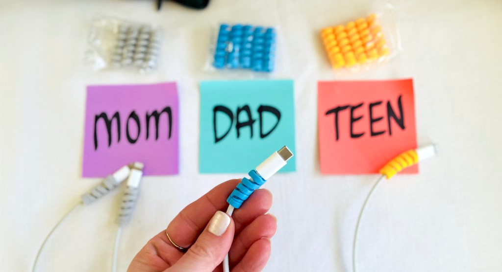 hand holding cord with blue silicone cord protector and other family members laying on background