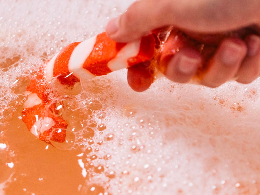 hand holding candy cane bar in bathtub