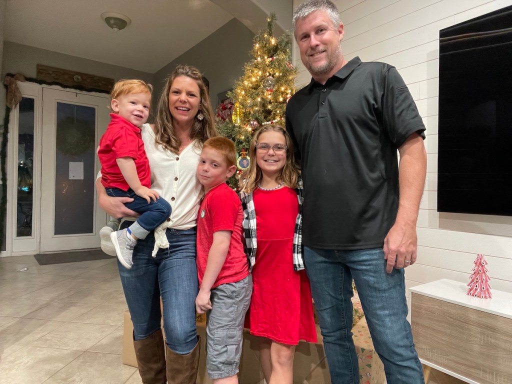 family dressed for christmas standing in front of tree