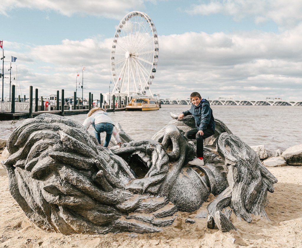 boy sitting on giant beach sculpture