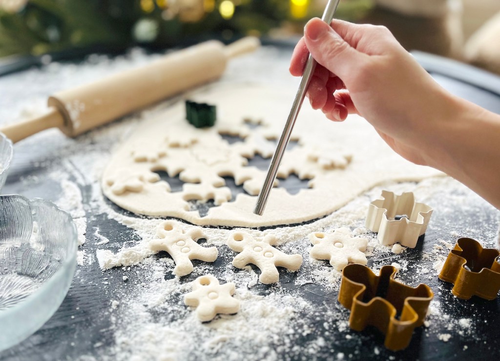 hand holding stainless steel straw cutting holes in dough shapes