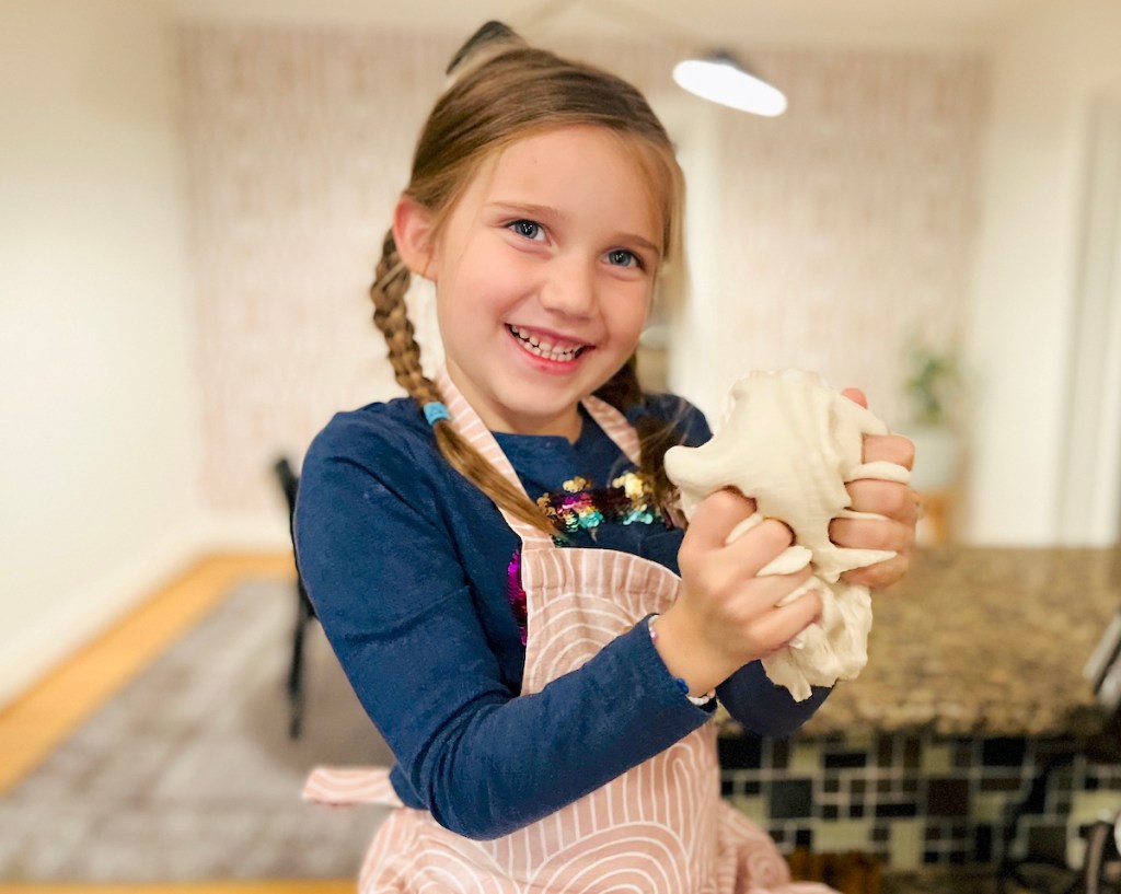girl holding salt dough on kitchen counter