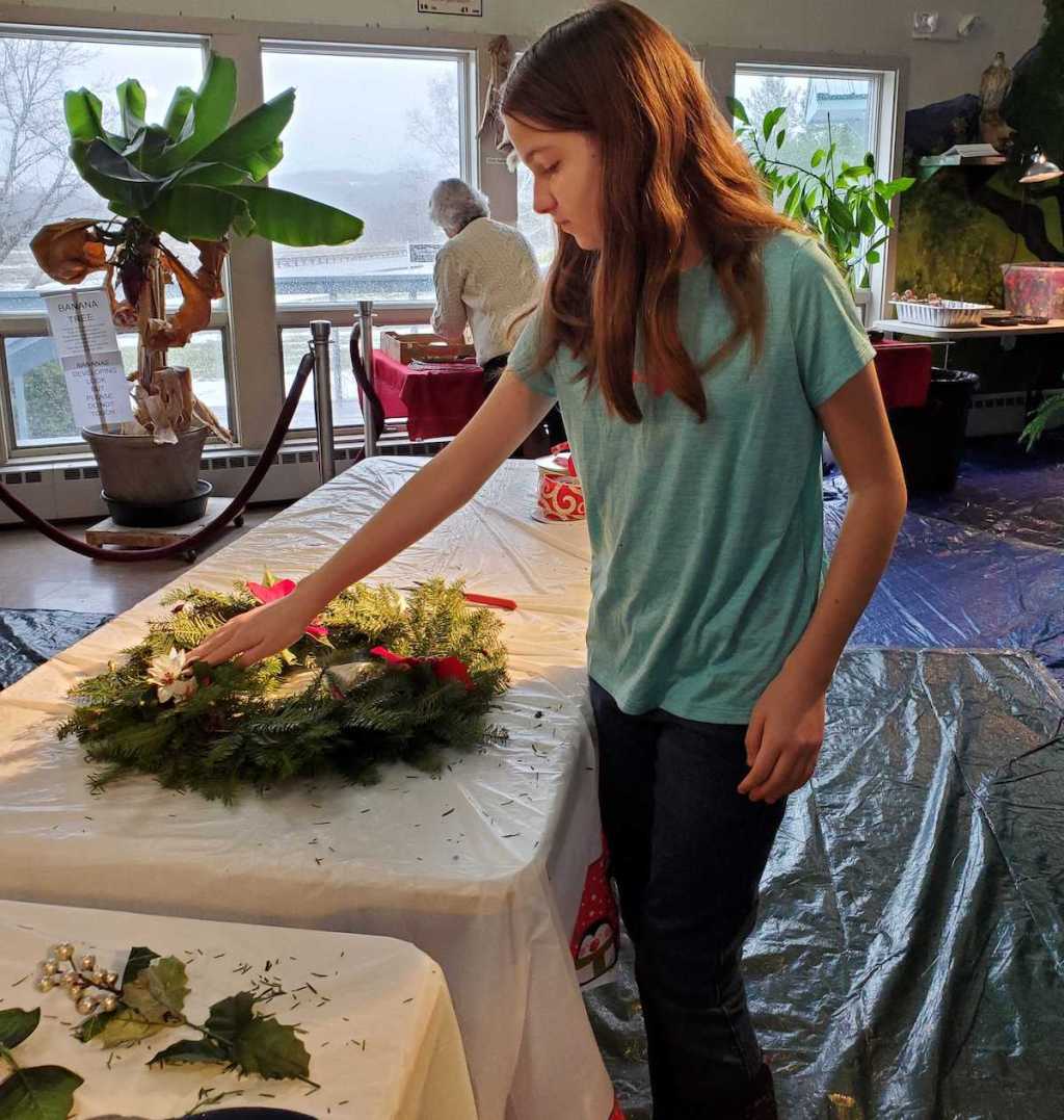 girl making christmas evergreen wreath