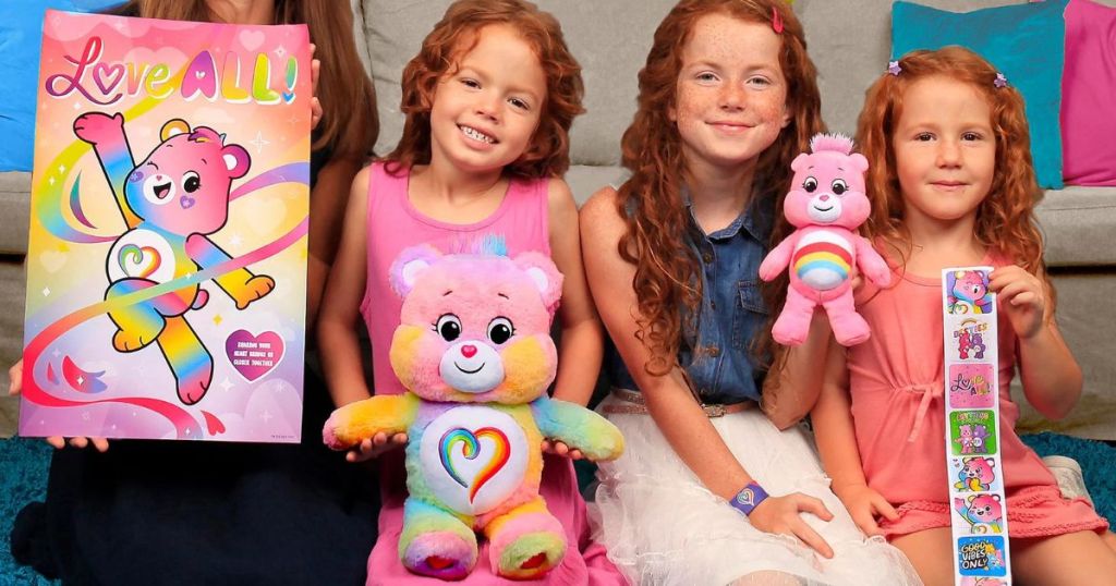 A woman and children holding Care Bears merchandise including 2 stuffed bears