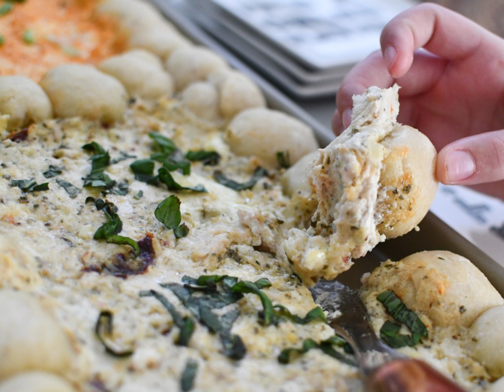 Grabbing a bite of cheese dip from a sheet pan