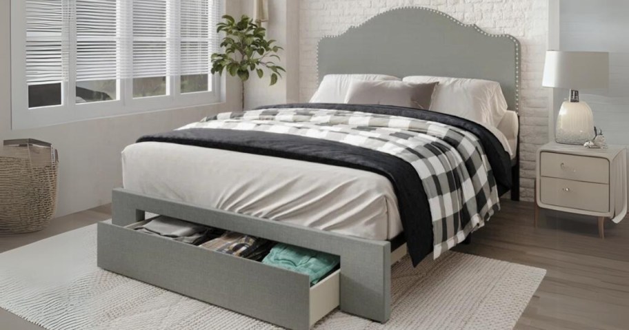 a grey upholstered bedframe and headboard with storage drawers at the front in a bedroom