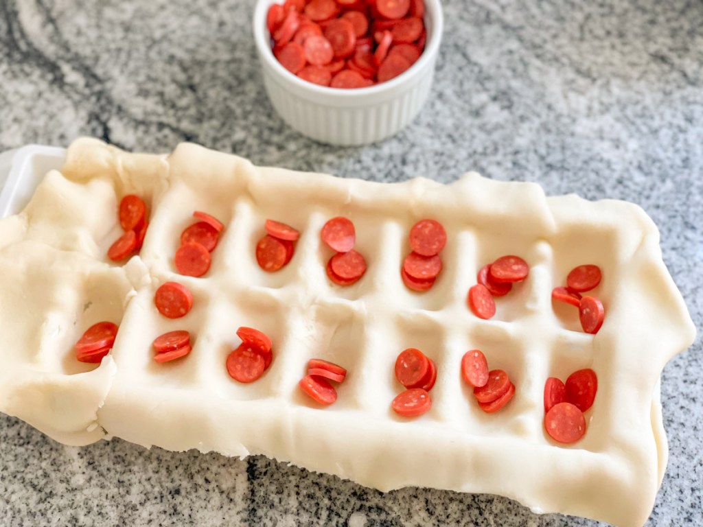 mini pepperoni added to pie dough in ice cube tray