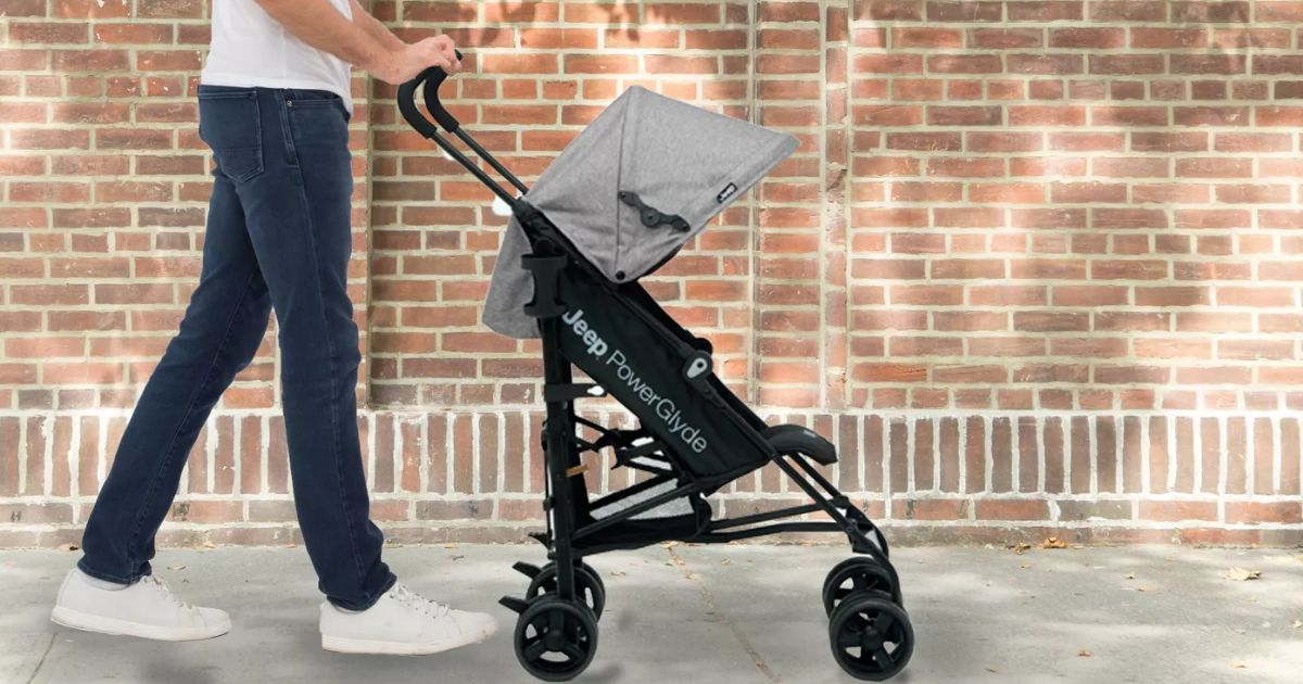 a man pushing a Jeep powerglyde stroller by delta children down the sidewalk