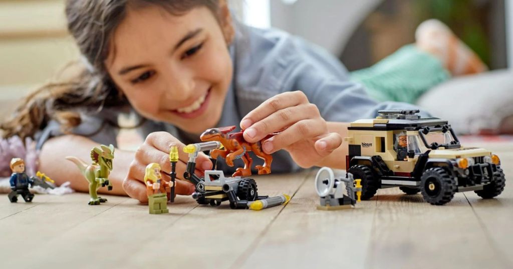 girl playing with lego dinosaur and vehicle set