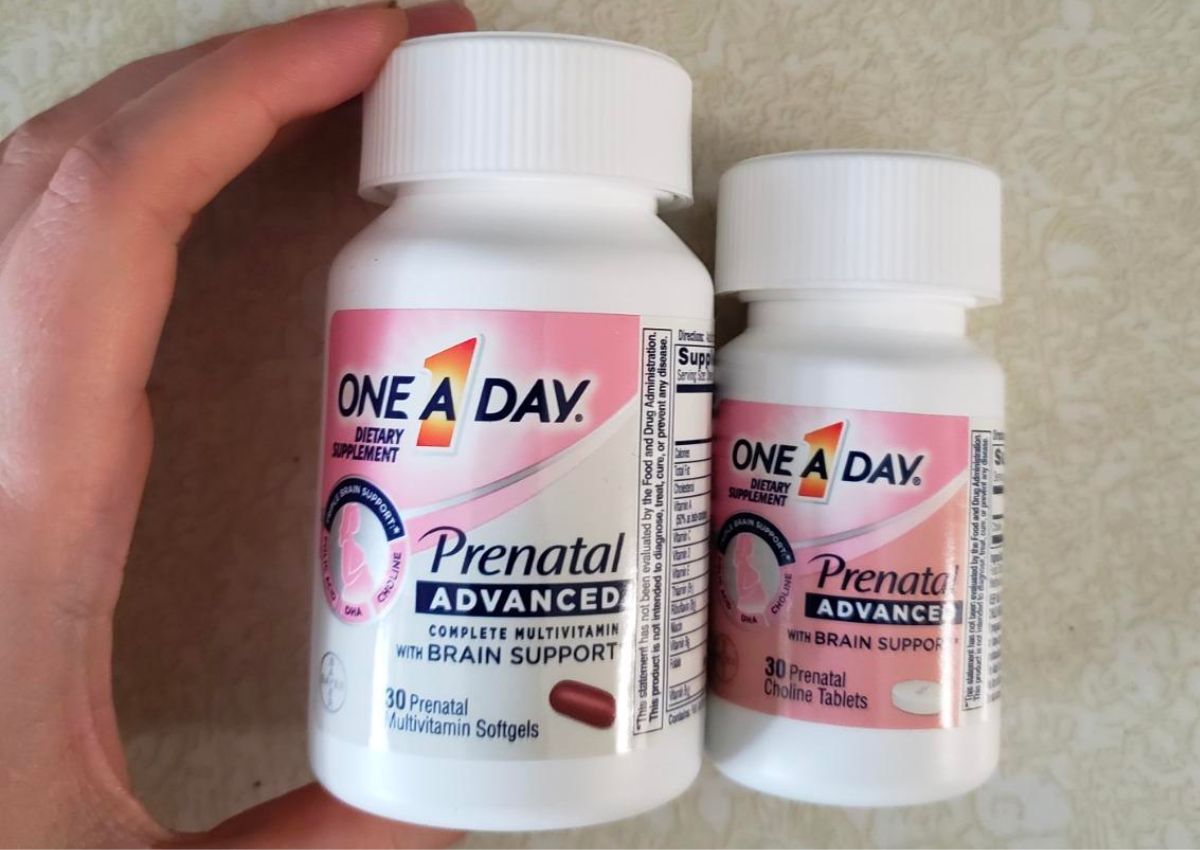a womans hand displaying a bottle of One A Day Womens&rsquo; Prenatal Advanced Complete Multivitamin next to a bottle of choline