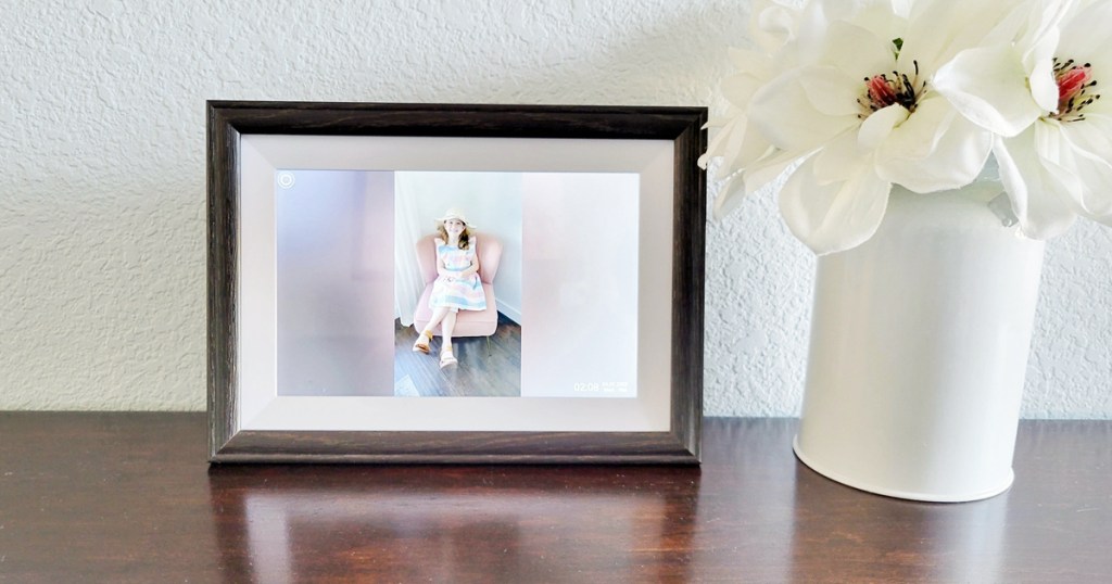 digital picture frame near vase of flowers