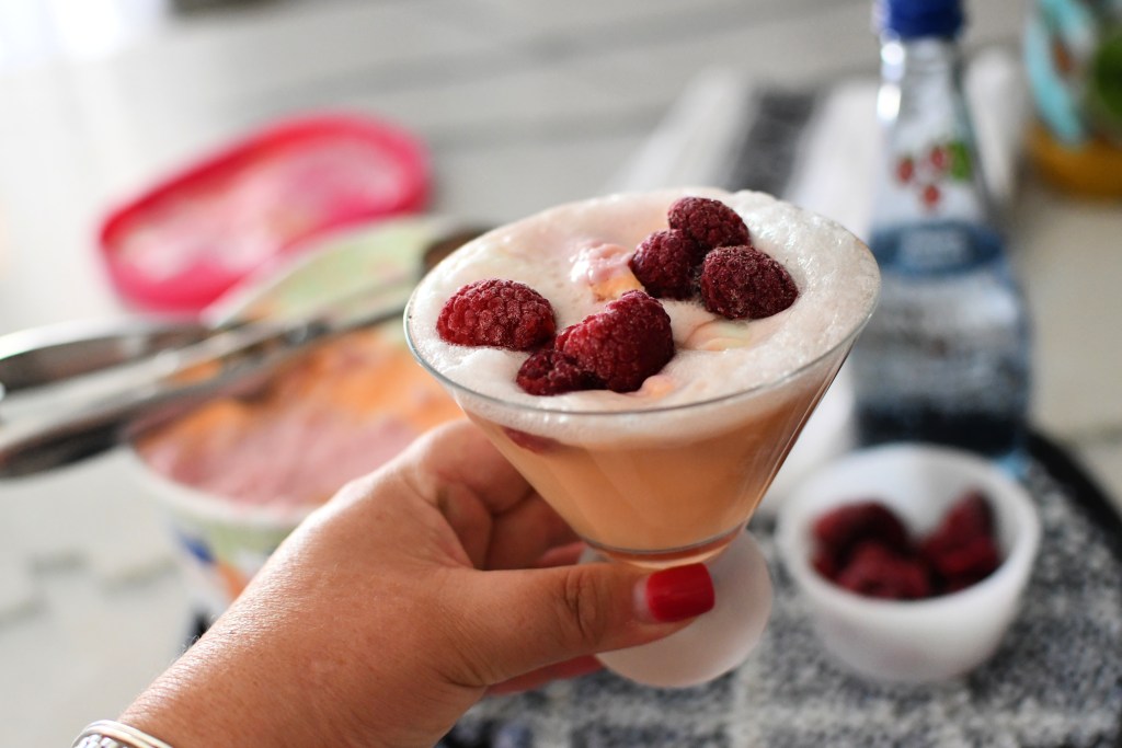 hand holding a raspberry sherbert mocktail, one of the best mocktails to make for the holidays