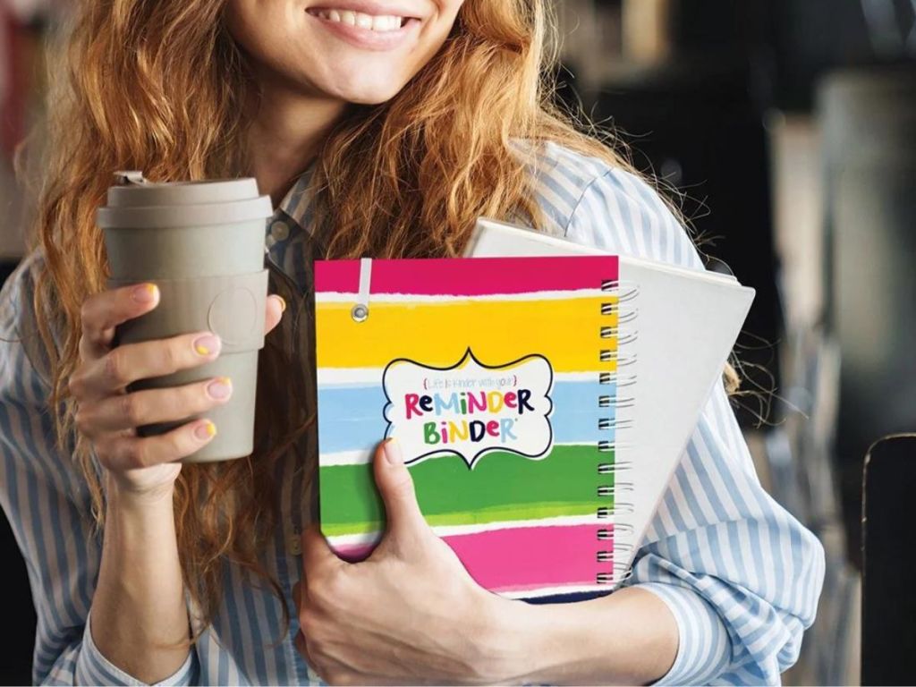 woman holding a reminder binder and a coffee