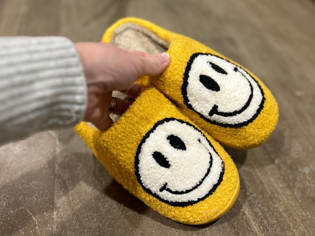 person holding up pair of Smiley Slippers in yellow