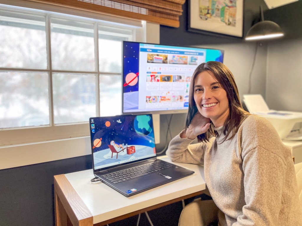 woman leaning on office desk with small and large monitors