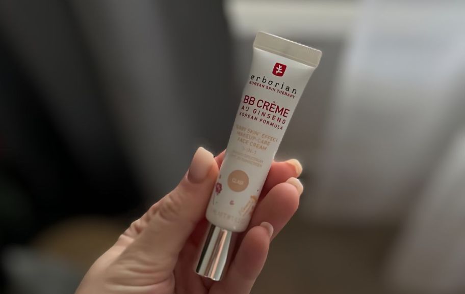 a womans hand holding a mini sized erborian bb creme