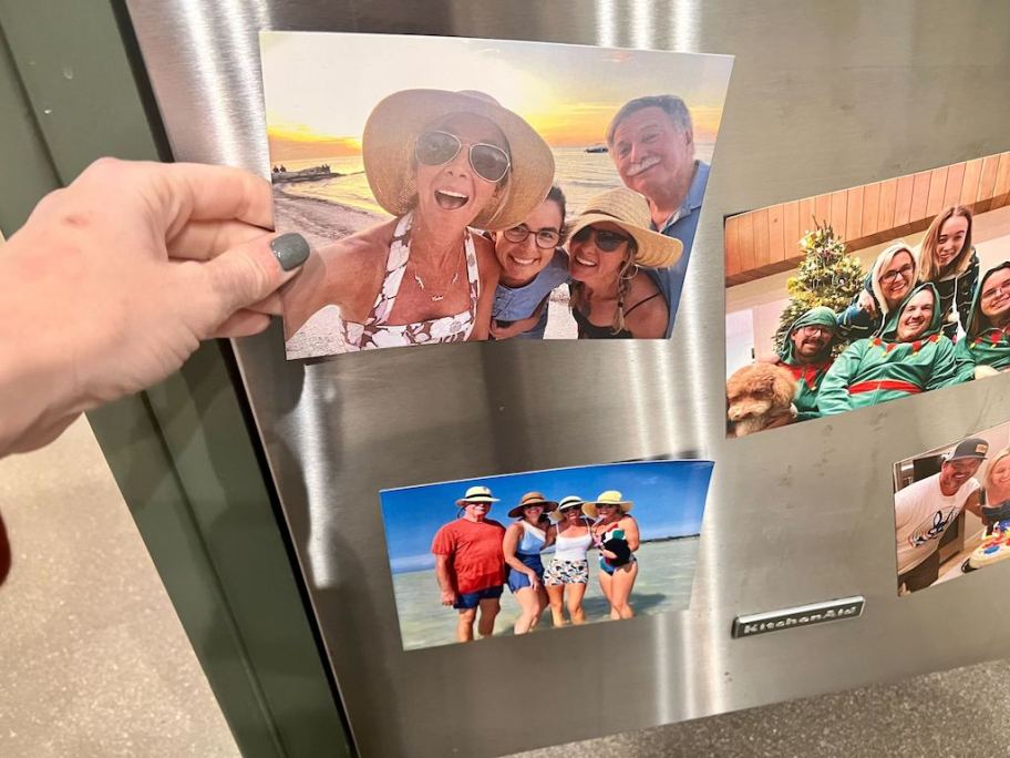 hand holding photo magnets to the fridge