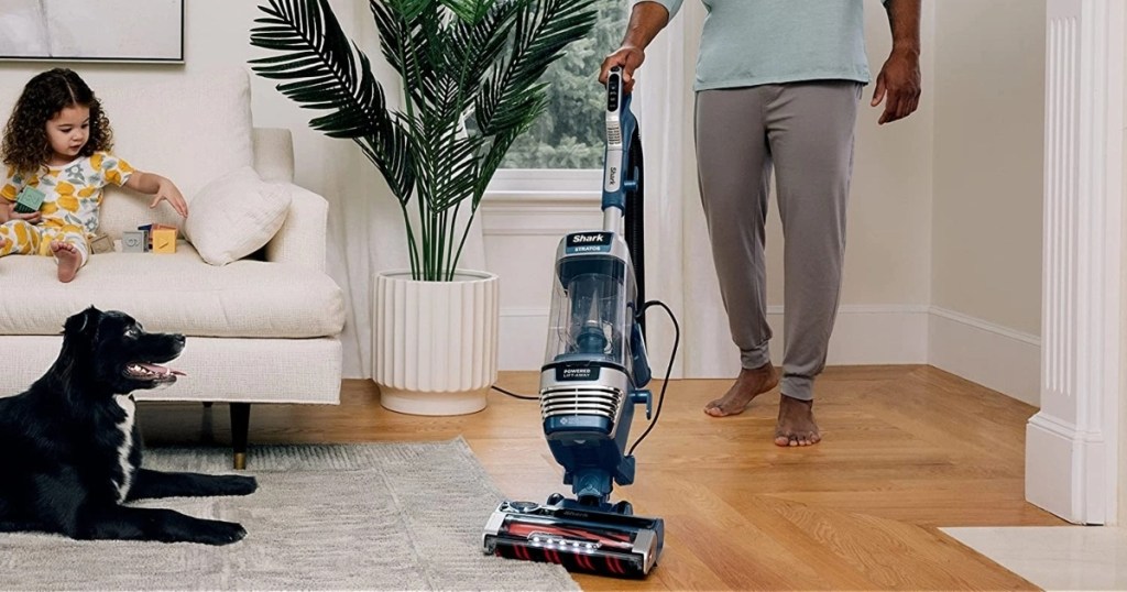 Man using vacuum near dog and child