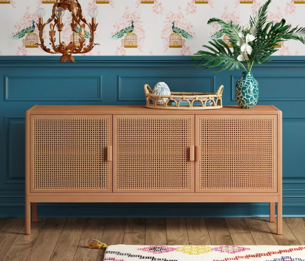 brown caned console table style against wallpaper and blue wall 