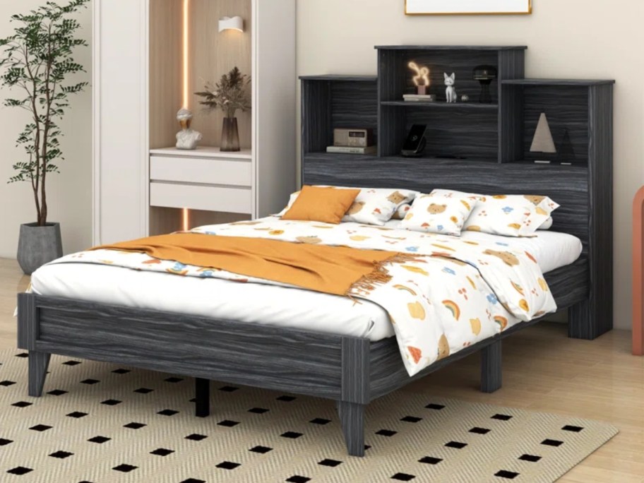 queen bed with a dark grey wood platform frame and bookcase headboard and yellow and white bedding on it