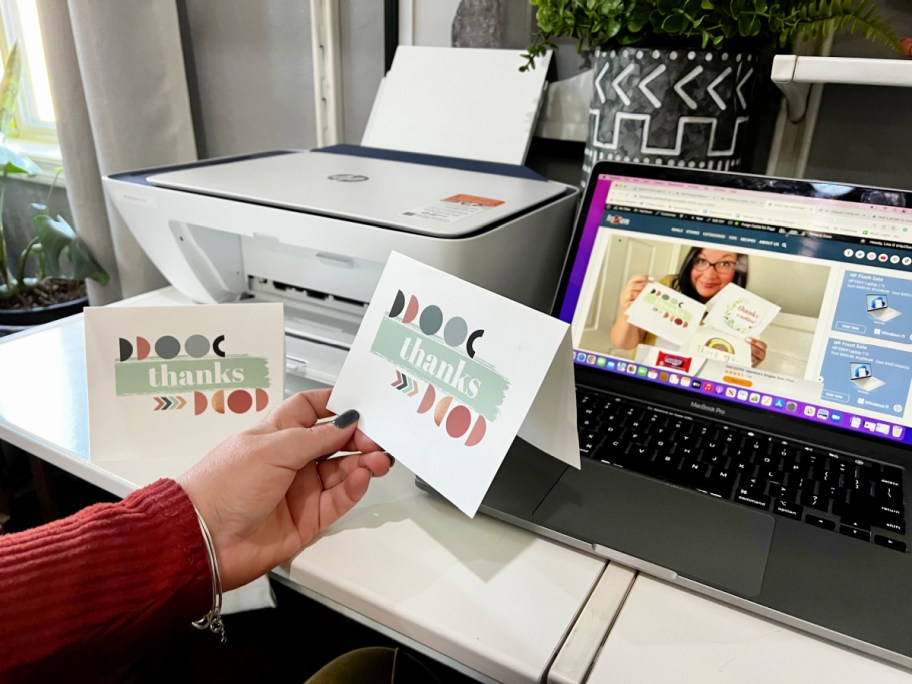 A woman is holding thank you cards printed on an HP printer.