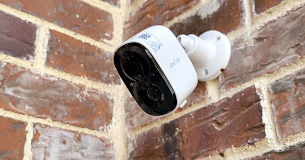 white and black security camera mounted on a brick outdoor wall
