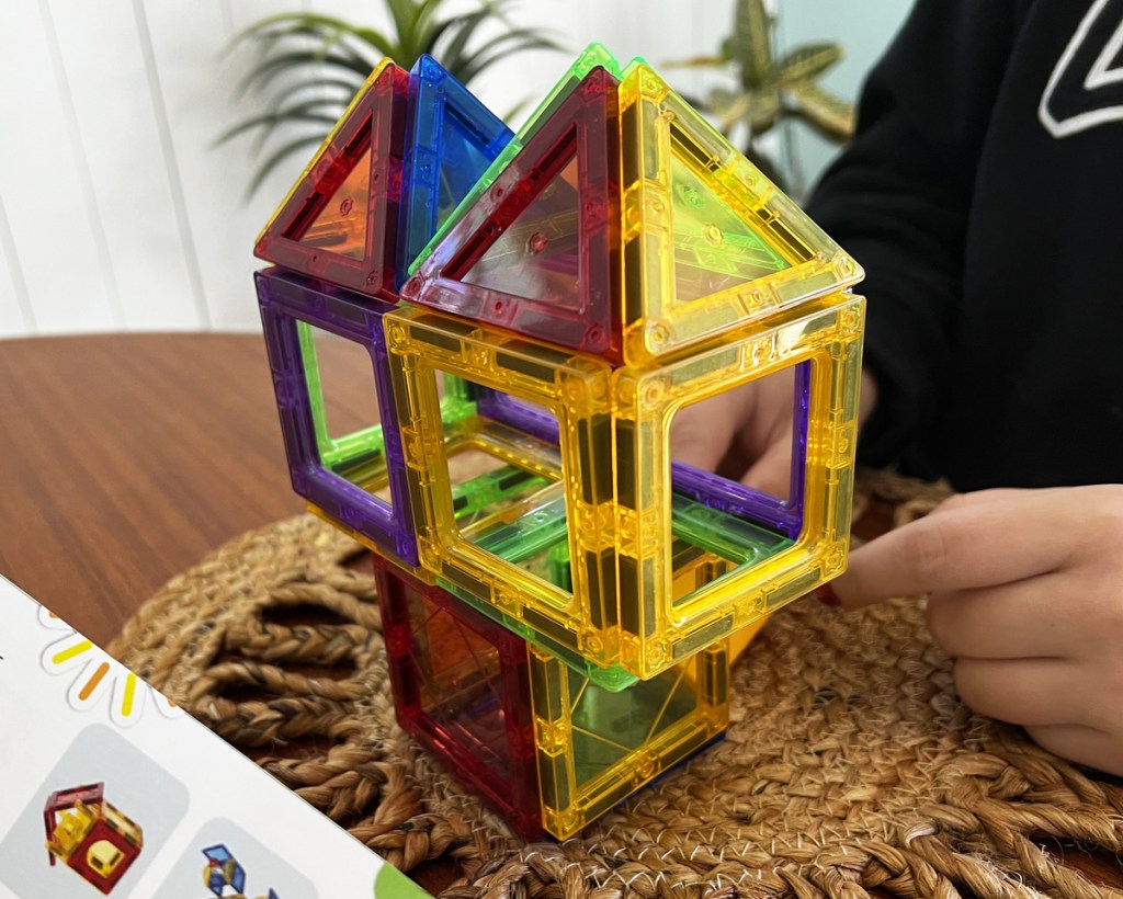 kid building tower out of magnetic tiles