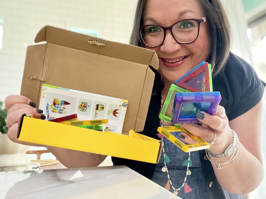 woman holding up box of magnetic tiles