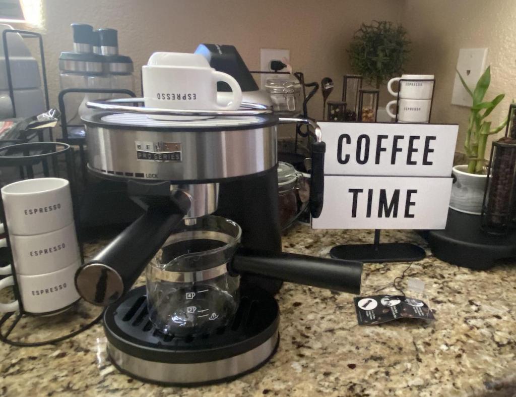 Espresso maker sitting on a counter with cups and a sign that says Coffee Time next to it