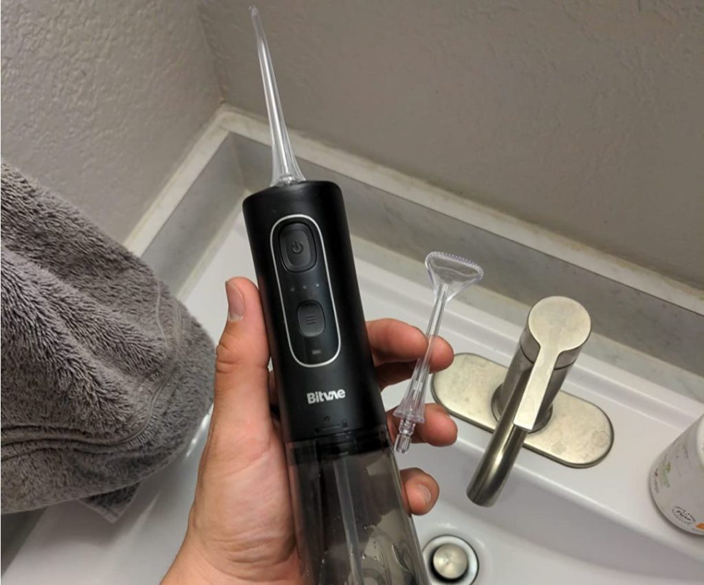 hand holding a Bitvae Water and tongue cleaning attachment over a sink