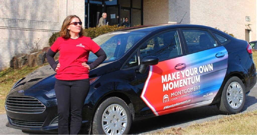Woman standing next to a vehicle with car advertising showing how to get paid to advertise on your car
